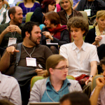 Two young men talking in a crowded lecture theatre