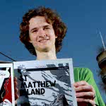 Low angle cartoonist Stuart McMillen holding comic.