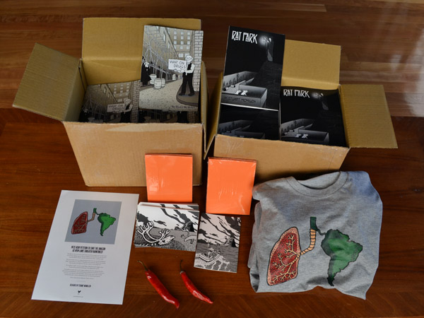 A look at some of the rewards from my crowdfunding campaign. Doesn't include the wall prints. Note that the chillies were not sent to any supporters! The document on the bottom left is the Made in the New t-shirt certificate of authenticity. Rat Park crowdfunding merchandise: printed comics, greeting cards and t-shirt featuring Stuart McMillen artwork.