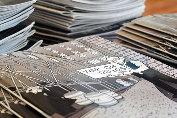 I don't think many kids are named Milton these days. I wonder why that is? Photograph of comic book cover with shallow depth of field. War on Drugs comic by Stuart McMillen. Cartoon Milton Friedman character.